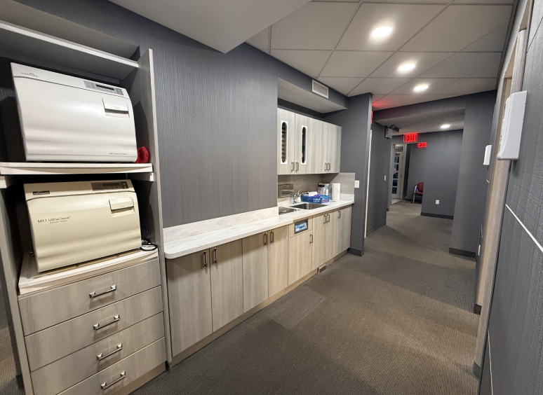Modern office kitchen area with cabinets and appliances.
